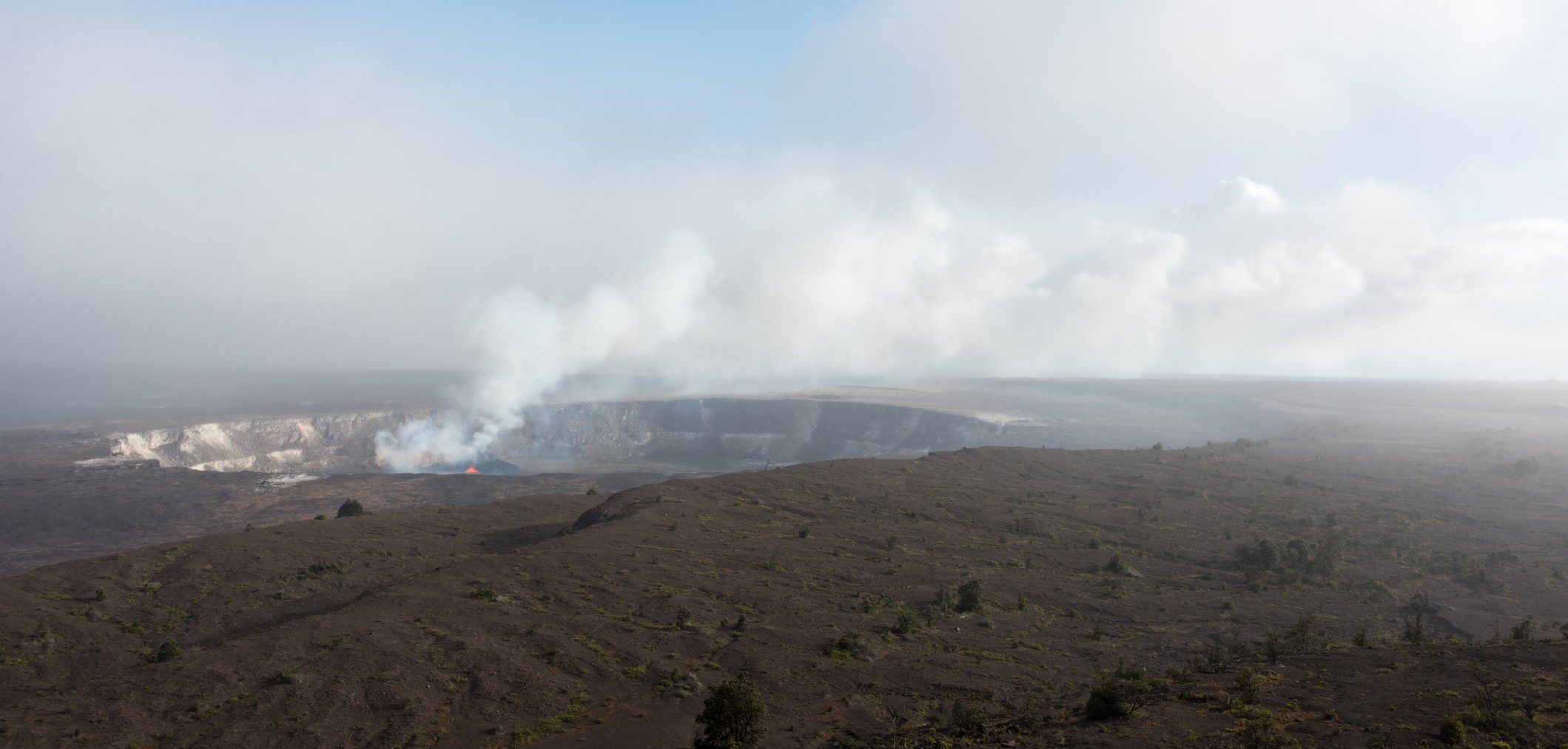 Smoke rising from a vast volcanic landscape