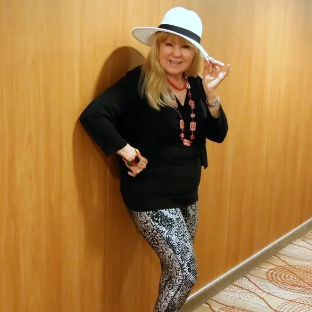 Smiling woman leans against wooden wall
