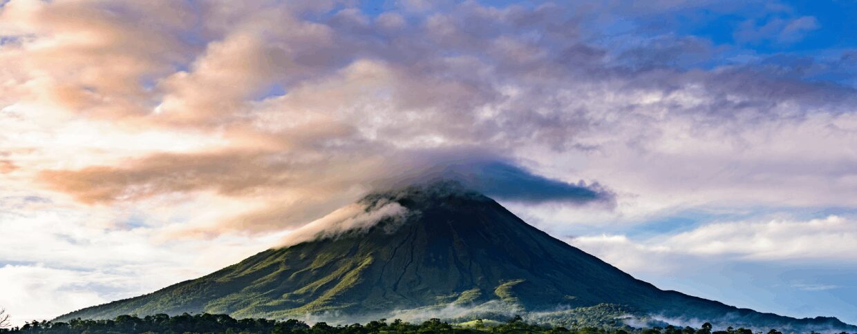 Mountain with clouds under colorful sky.